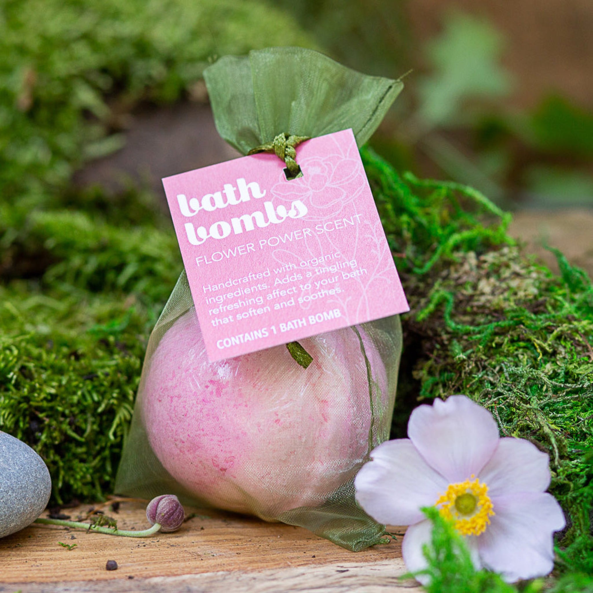 A pink bath bomb with a label that reads 'BATH BOMBS Flower Power'.