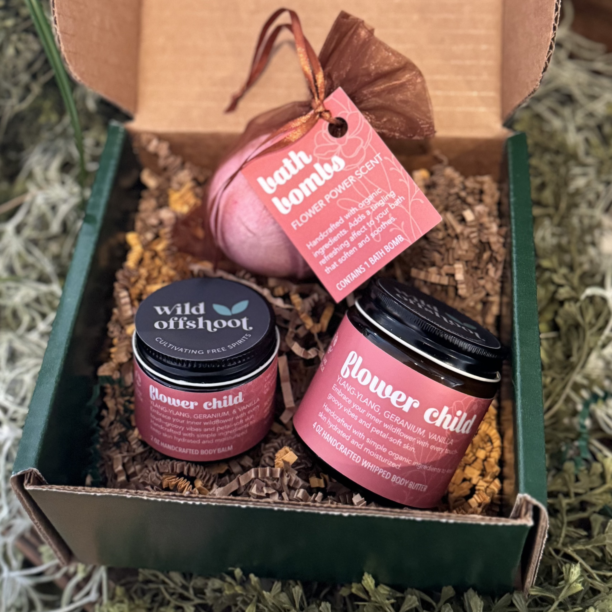 An open box that shows a jar of Wild Offshoot Flower Child balm, butter and a Flower Power bath bomb